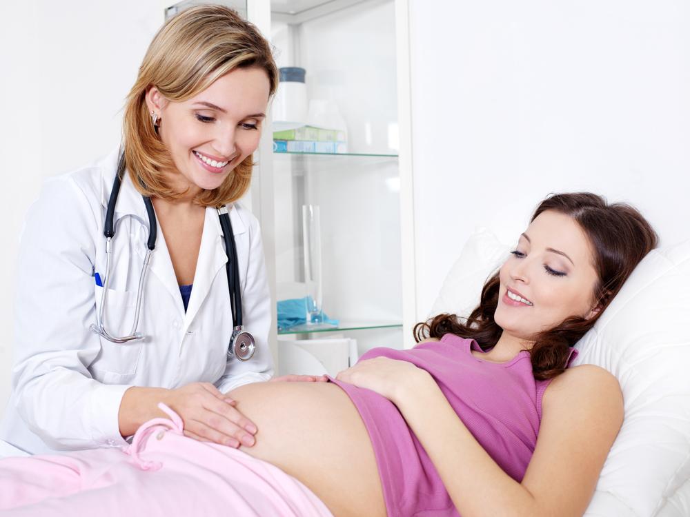 医生关心医院里的年轻孕妇——在室内